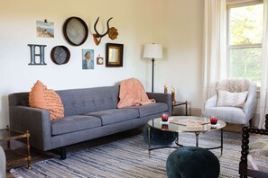 Una sala de estar con un sofá gris, una mesa de centro redonda y un tapete estampado.