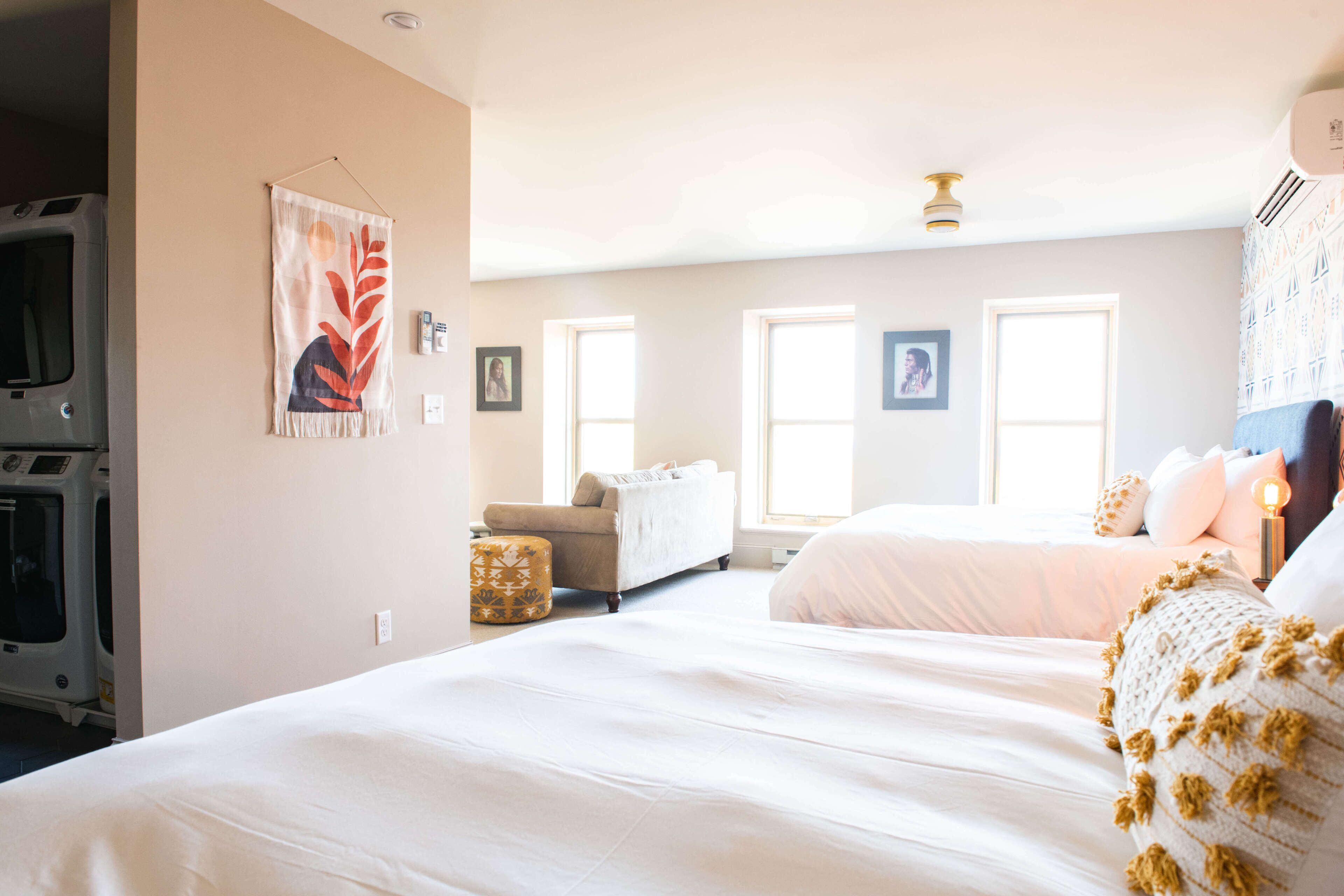 Une chambre avec un grand lit, un canapé et un lave-linge placé dans un coin.