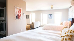 A bedroom with a large bed, a sofa, and a washing machine in the corner. - Hale House, Customizable Historic Gem in downtown Bayfield (Bayfield)