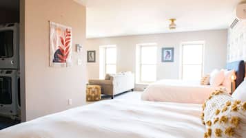 Une chambre avec un grand lit, un canapé et un lave-linge placé dans un coin.