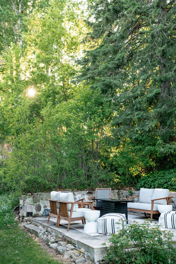 Un área de estar al aire libre con muebles de madera y una pared de piedra.