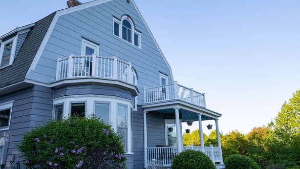 A two-story house with a bay window, a porch with white railings, and a small balcony. - Hale House, Customizable Historic Gem in downtown Bayfield (Bayfield)