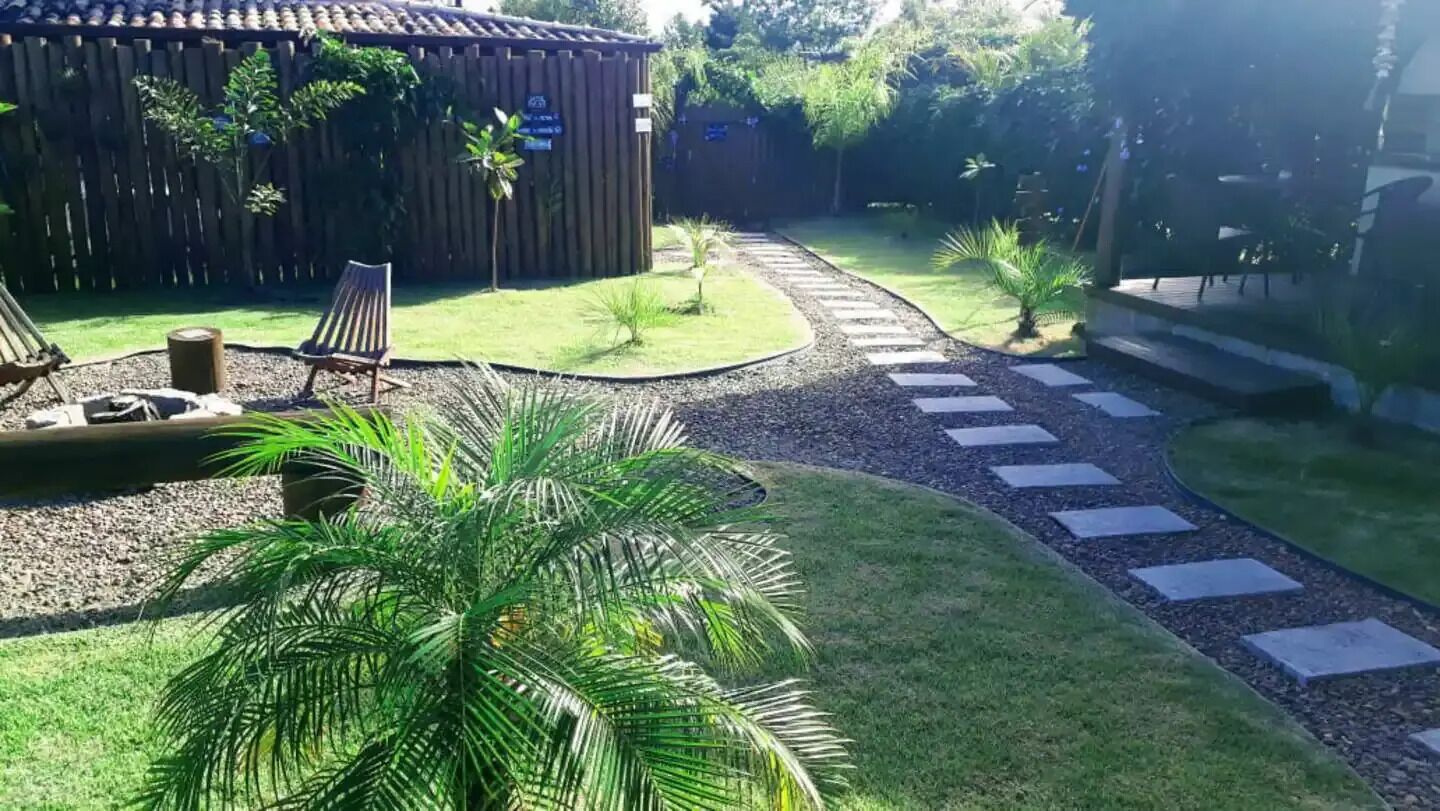 A garden with a paved path, a wooden fence, and a seating area with chairs.