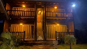 A two-story building with a balcony on each floor, a staircase leading to the entrance, and a sign indicating various amenities. - Altos da Lagoa-praia do Rosa, Ibiraquera -studio 2 (imbituba)