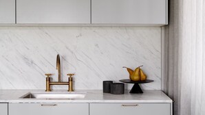Eine Küche mit Marmorarbeitsplatte, goldenen Armaturen und einer Obstschale.