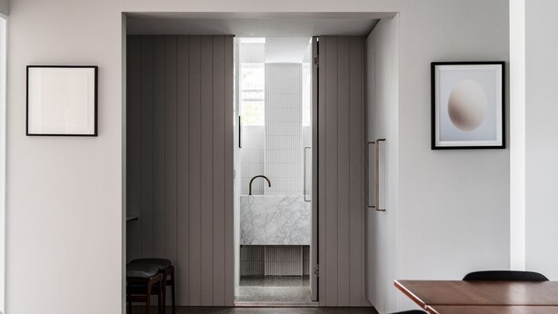 Ein modernes Interieur mit Küchenbereich, einem Esstisch und Blick ins Badezimmer.