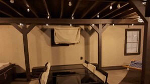 Une pièce chaleureuse avec une table à plateau en verre, des fauteuils confortables, un lit et un hamac.