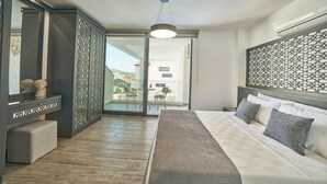 A modern bedroom with a large bed, a desk with a mirror, and a view to the outside.