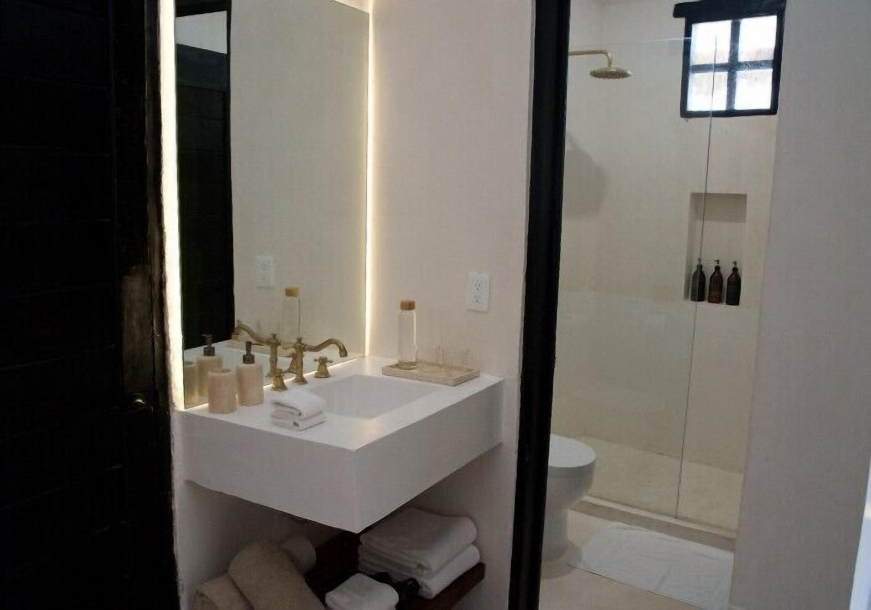 A modern bathroom with a white sink, mirror, and a glass-enclosed shower.