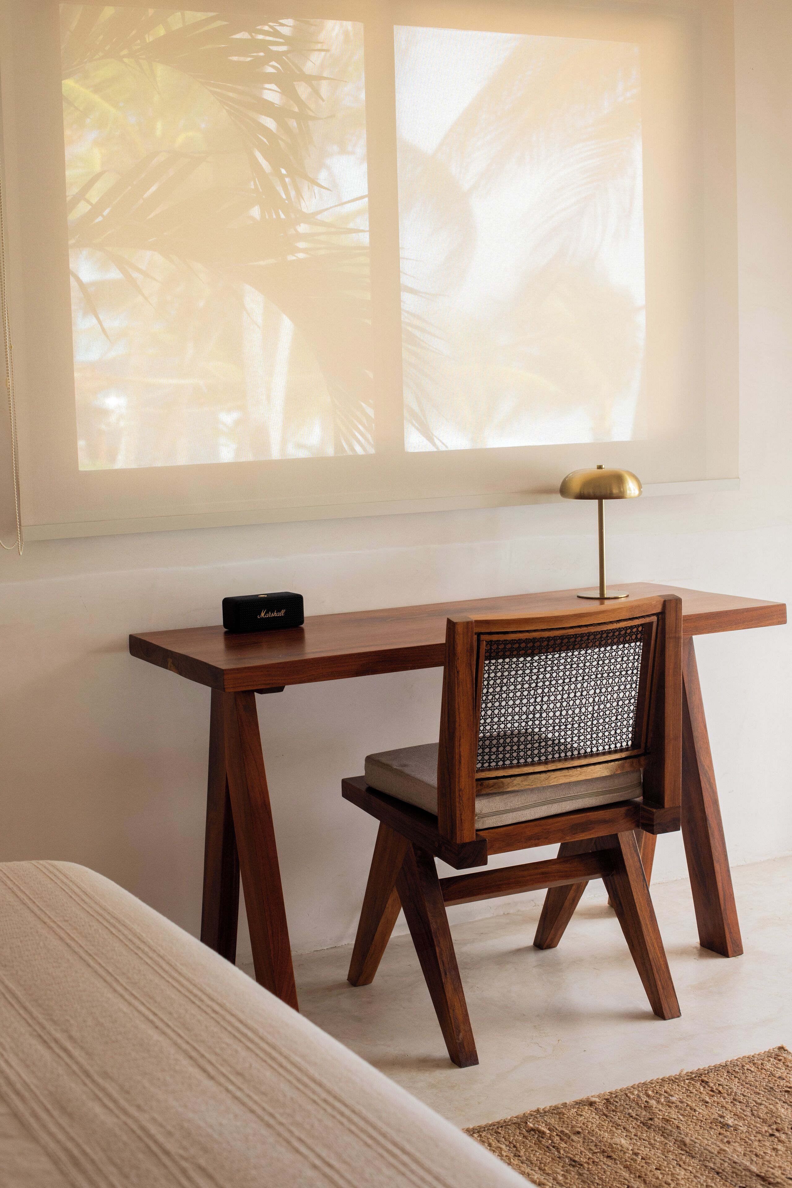 A wooden desk with a lamp, a chair, and a small speaker.