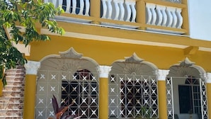 Un edificio de dos pisos con paredes amarillas y detalles decorativos blancos alrededor de ventanas y puertas.