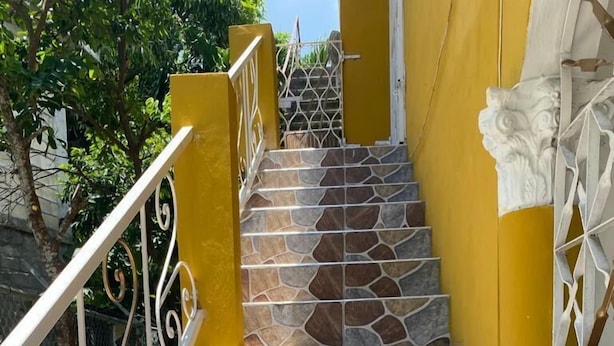 Una escalera con escalones de piedra y barandillas de metal blanco, que conduce a una puerta con un revestimiento blanco decorativo.