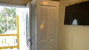 Una habitación con suelo de baldosas blancas, un armario blanco y un televisor montado en la pared.
