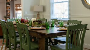 Een eetkamer met een houten tafel voor zes personen, omringd door groene stoelen.