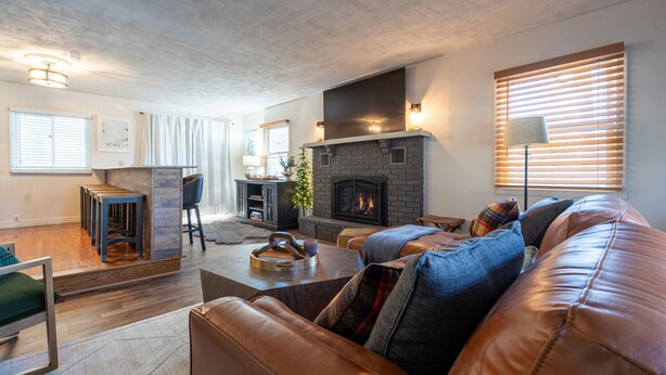 Een moderne woonkamer met een open haard, een leren bank en een eethoek met een tafel en stoelen.