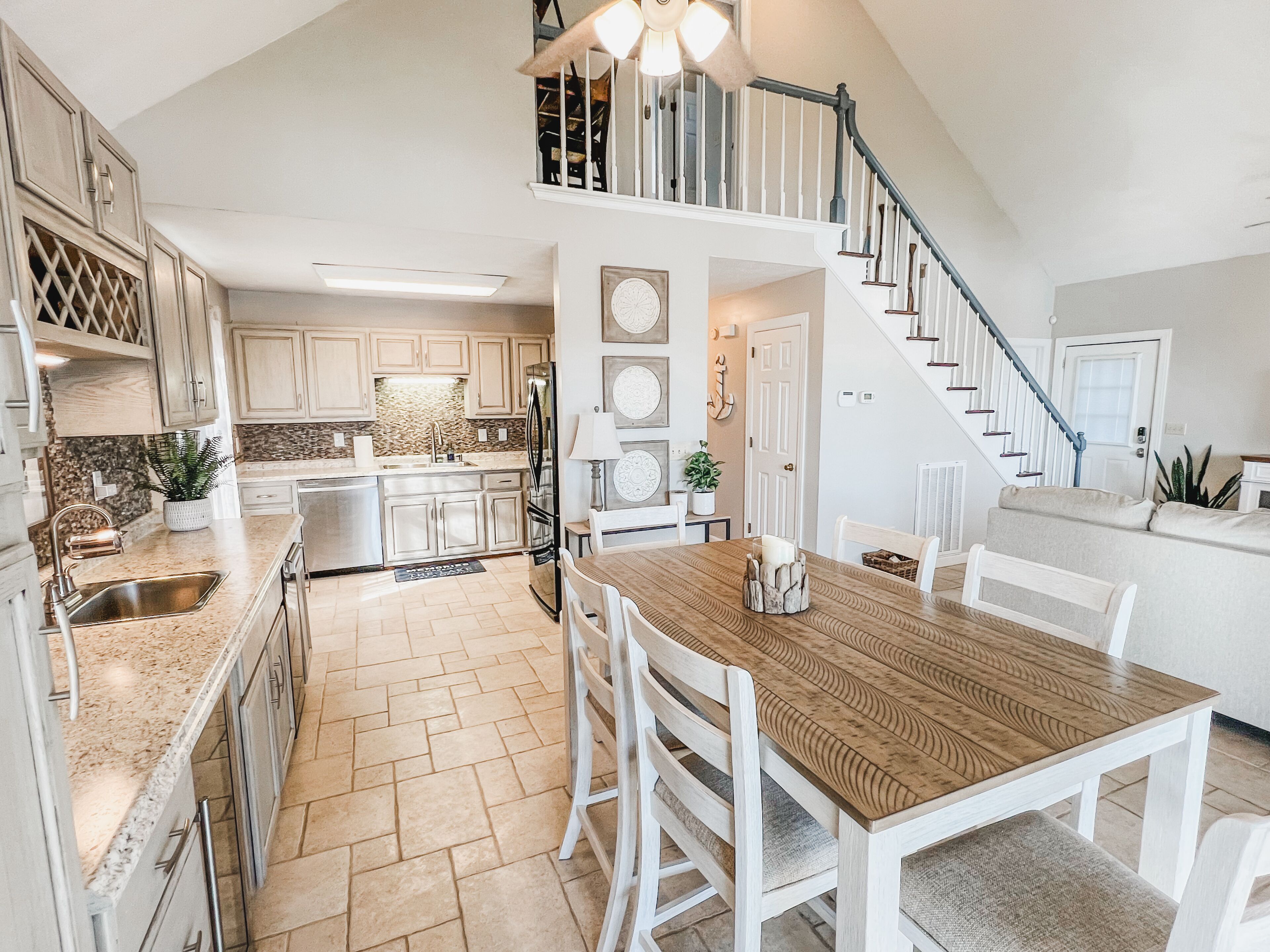 A spacious kitchen with a dining area, a staircase, and a living room.