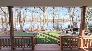 Une terrasse couverte avec vue sur un lac, un barbecue et des sièges d’extérieur.