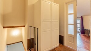 Un couloir avec une armoire blanche, une rambarde noire et une porte donnant sur une autre pièce.