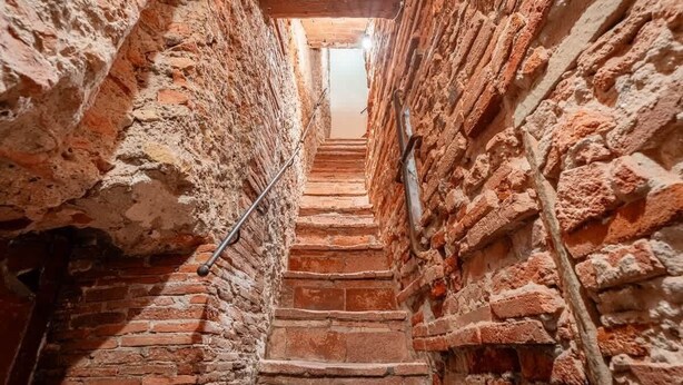A narrow brick staircase in a building with exposed brick walls and wooden beams. - Room Flavia all'Anfiteatro - Affitti Brevi Italia (Lucca)