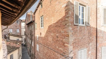 A narrow alleyway between buildings with brick facades and white shutters.