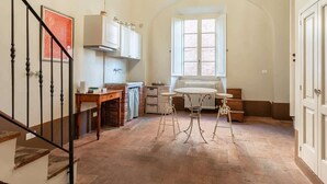 A kitchen with a wooden table, a radiator, and a window. - Room Flavia all'Anfiteatro - Affitti Brevi Italia (Lucca)