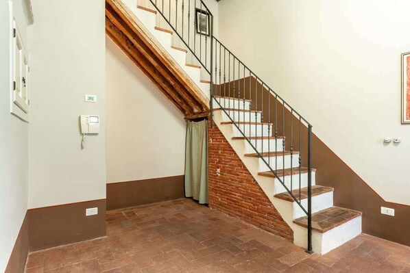 Un escalier avec des marches en bois et une rampe en métal, menant à l’étage supérieur.