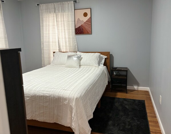 A neatly made bed with white bedding, a bedside table with a lamp, and a wall-mounted picture. - 2 Bedroom-near Hospitals, Six Flag, Big E (Springfield)