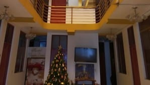 A multi-level hotel interior with balconies, a Christmas tree, and a fireplace. - Hostal Mansion Dorada (Tacna)