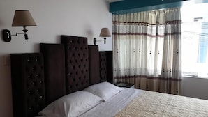 A bedroom with a large bed, two wall-mounted lamps, and a window with curtains. - Hostal Mansion Dorada (Tacna)