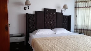 A hotel room with a large bed, two bedside tables, and wall-mounted lamps. - Hostal Mansion Dorada (Tacna)