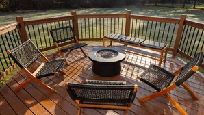 Une terrasse en bois avec un foyer et quatre chaises.