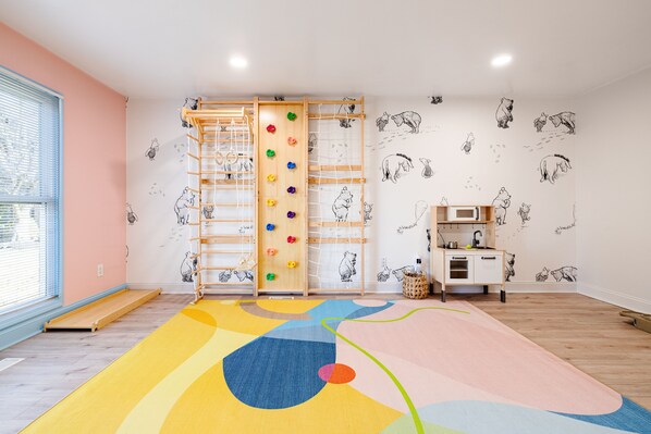A child-friendly room with a climbing wall, a colorful play mat, and a kitchen area. - Sauna~IndoorPlayArea~GameRoom~FirePit~23miZoo~SpookyNook~KingsIsland~VOA~BigYard (Liberty Township)
