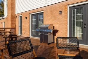A patio with a grill, outdoor seating, and a brick building. - Sauna~IndoorPlayArea~GameRoom~FirePit~23miZoo~SpookyNook~KingsIsland~VOA~BigYard (Liberty Township)