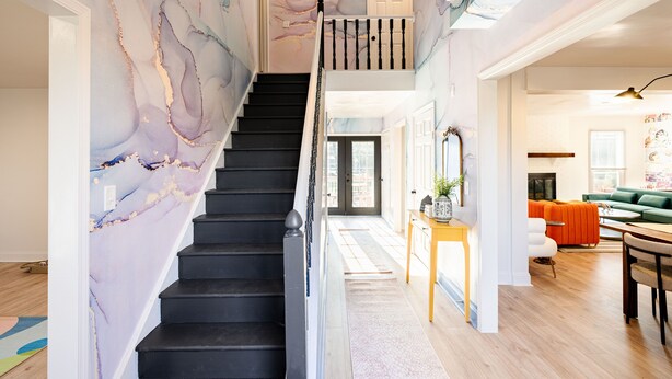 Un escalier orné d’un motif en marbre mène au deuxième étage. On aperçoit, au premier plan, une table en bois sur laquelle est posée une plante.