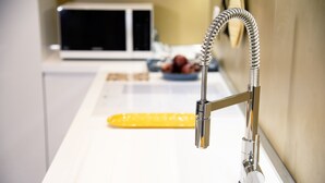 Un évier de cuisine doté d’un robinet moderne et d’un outil de nettoyage jaune.