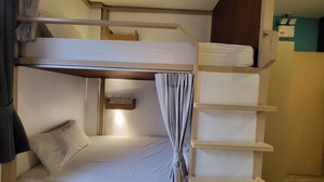 A bunk bed with a headboard, a bedside table with a lamp, and a curtain. - Terminal 58 hostel at town (Phuket)