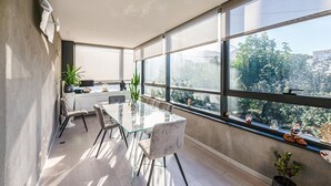 Une cuisine moderne dotée d’une grande fenêtre, d’un coin repas avec une table en verre et offrant une vue sur la verdure environnante.