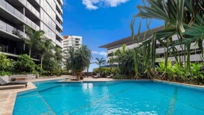 Une piscine entourée de verdure et de bâtiments modernes.