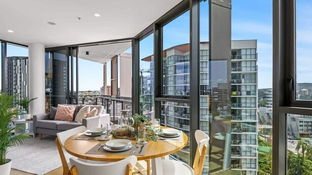 Un salon moderne avec un coin repas, de grandes fenêtres et une vue sur la ville.