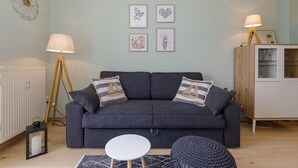 A modern living room with a dark grey sofa, two matching pillows, a small round table, and a floor lamp.