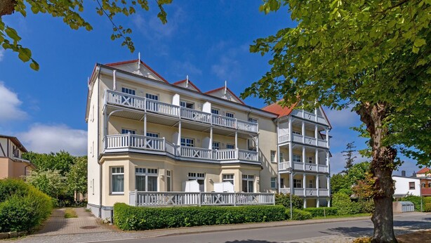 A multi-story hotel with balconies, a cobblestone pathway, and surrounding greenery.