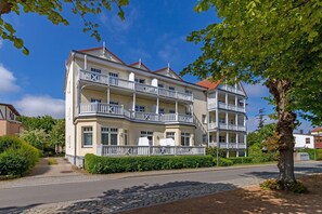 A multi-story hotel with balconies, a cobblestone pathway, and surrounding greenery. - Ferienwohnung Parkblick 26 - Villa Parkblick (Kühlungsborn)