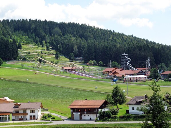 A rural landscape with a ski lift, houses, and a forested hill. - Lula inklusive Schwimmbad und Sauna by Interhome (Sankt Englmar)
