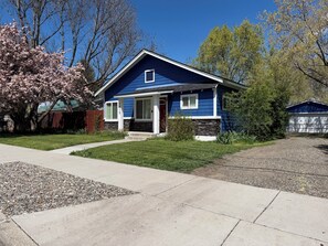 A residential house with a front porch, a stone foundation, and a driveway.