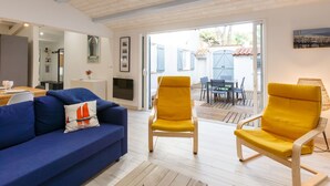 Una sala de estar moderna con un sofá azul, sillones amarillos y un comedor con mesa y sillas.