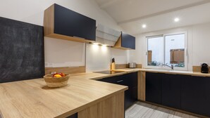 Una cocina moderna con encimera de madera, un frutero y una ventana que deja entrar luz natural.