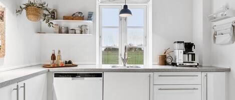 Kjøleskap, ovn, oppvaskmaskin og høy barnestol