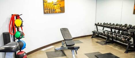 A gym with exercise equipment, a bench, and a wall-mounted painting.