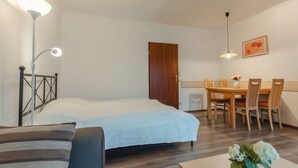 A bedroom with a bed, bedside table, lamp, and a dining area with chairs and a table. - Landhaus St. Georg by Interhome (Bad Gastein)