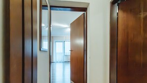 A hallway with wooden doors and a view into a room with a large window and a white ceiling. - Landhaus St. Georg by Interhome (Bad Gastein)